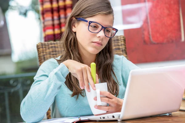 Ładna studentka odrabiania lekcji w domu z laptopem i picie herbaty Obraz Stockowy