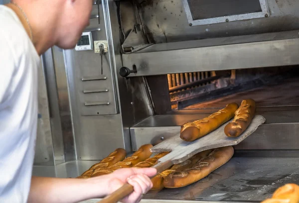 Пекарь удаляет из духовки вкусную хрустящую золотую палочку — стоковое фото