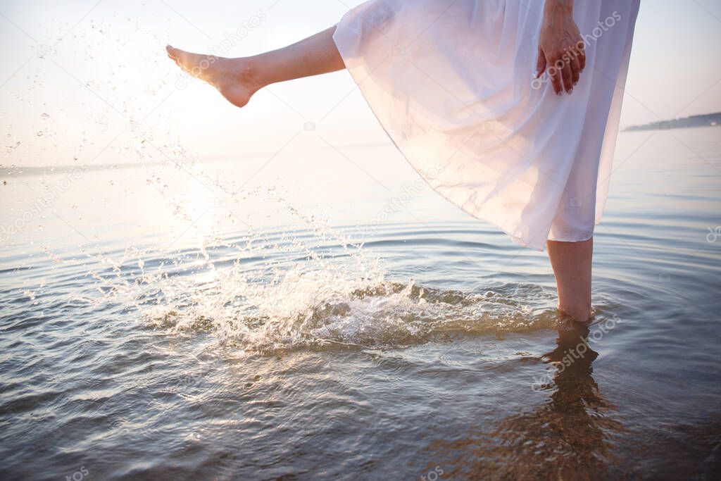 girl makes water splashes at sunset