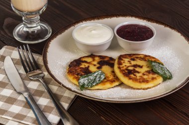 Ekşi krema reçelli peynirli kekler ve rustik arka planda kahve.