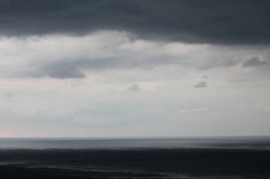 Kara gökyüzü ve yağmurdan önceki dramatik kara bulut. Kumsala yağmur yağıyor.