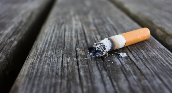 Selektywny fokus na papierosa tyłek z popiołu na białym tle na drewniane oparcie — Zdjęcie stockowe