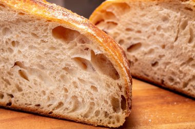 Ev yapımı ekşi ekmek somunu fırında pişirildikten sonra şef tarafından kesme tahtasına dilimleniyor.