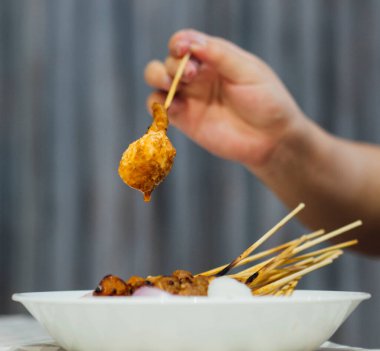 Çubukta satay, elinde pirinç, elinde ketupa