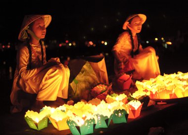 Two small kids selling handmade lanterns to tourists in the streets at July 23, 2013 in Hoi An, Quang Nam, Vietnam.