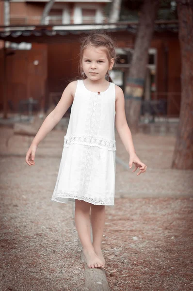 Красивая маленькая девочка в белом платье ходит босиком по полю — стоковое фото