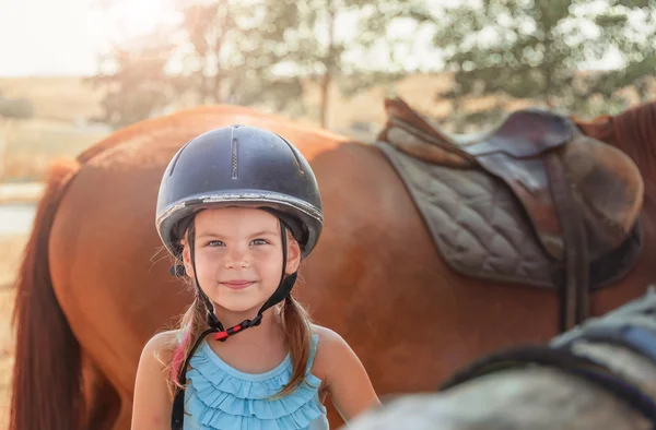 小さな女の子と茶色の馬の肖像画。E のヘルメットを持つ少女 — ストック写真