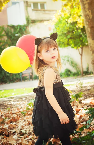 Красивая маленькая девочка, одетая как кошка с шариками в руках. Милая улыбка, нежный взгляд . — стоковое фото