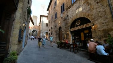 SAM GiMIGNANO, İtalya - 20 Temmuz 2015: 20 Temmuz 2015 tarihinde Tuscan 'ın surlu kenti San Gimignano' da sokak. Turistler bu geleneksel İtalyan şehrindeki dükkanlara bakarak sokaklarda dolaşıyorlar..