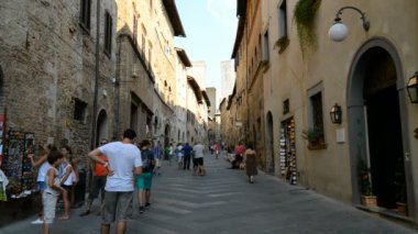 SAM GiMIGNANO, İtalya - 20 Temmuz 2015: 20 Temmuz 2015 tarihinde Tuscan 'ın surlu kenti San Gimignano' da sokak. Turistler bu geleneksel İtalyan şehrindeki dükkanlara bakarak sokaklarda dolaşıyorlar..