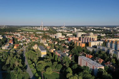 Çek Cumhuriyeti Prag 'daki Maleice bölgesinin hava aracı görüntüsü, yaz günü günbatımında konut binaları, yeşil şehir parkı ve endüstriyel bacaları gösteriyor..