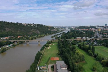 Açık bir yaz gününde, Prag 'ın Vltava Nehri, golf sahası, yeşil parklar, köprüler ve çevre bölgelerdeki hava aracı görüntüsü.