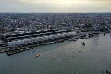 Amsterdam Centraal İstasyonu 'nun havadan görünüşü ve Hollanda, Amsterdam' da kanallar, rıhtım, botlar ve yoğun kentsel mimari ile tarihi şehir merkezi.