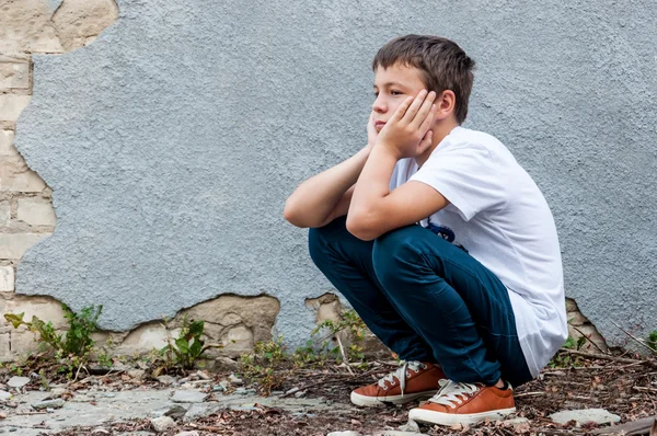 Грустный подросток на улице возле стены — стоковое фото