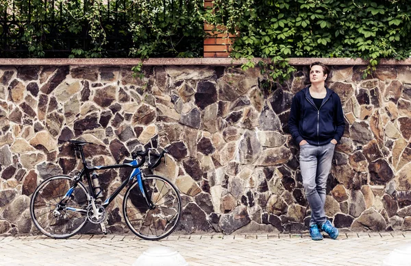 Giovane con bicicletta in piedi vicino al muro — Foto Stock