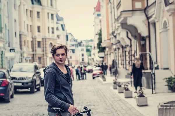 Jovem com uma bicicleta em uma rua da cidade — Fotografia de Stock