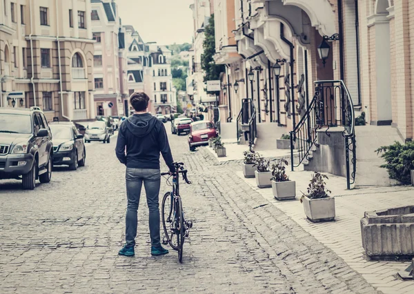 Молодой человек с велосипедом на городской улице — стоковое фото