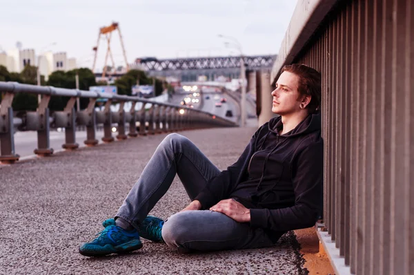 젊은 남자는 울타리 근처에 앉아 — 스톡 사진