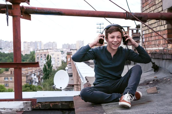 Підліток на даху будинку в навушниках — стокове фото