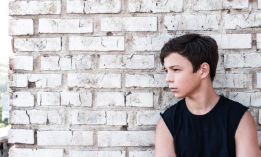 bir tuğla duvar yakınındaki dalgın genç