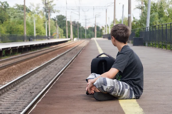 Подросток ждет поезд до станции — стоковое фото