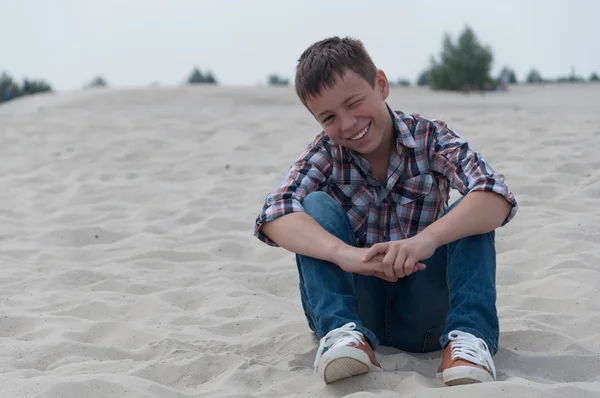 Портрет подростка, сидящего на песке Стоковое Фото