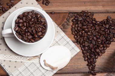 Beyaz fincan ve bir ahşap yüzeyde kahve taneleri