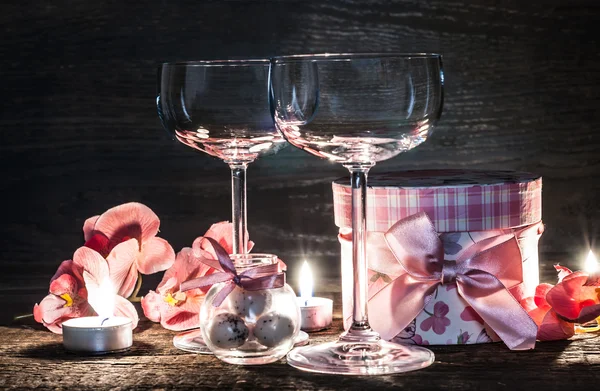Wijnglazen, cadeau en kaarsen voor de romantische avond — Stockfoto