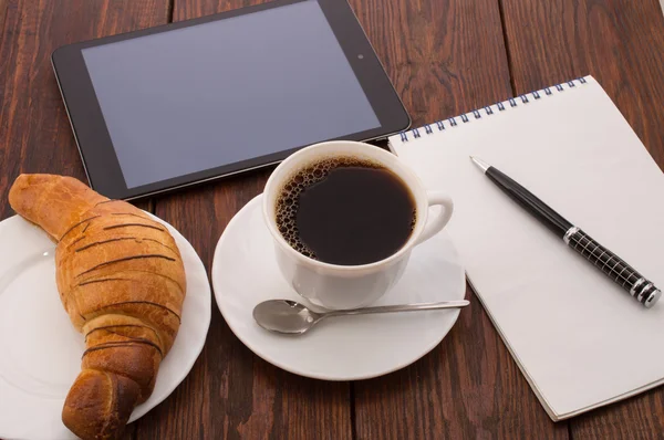 Desayuno con taza de café negro, croissants y notebook — Foto de Stock