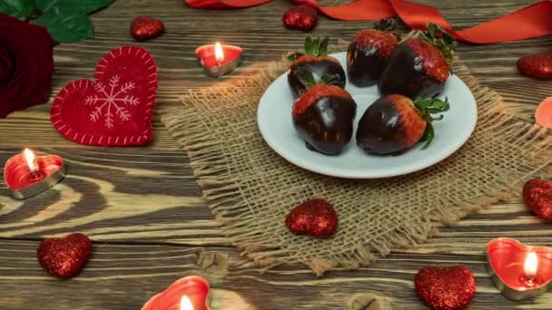 Szent Valentin nap. Doboz csokoládéval borított eper, szív, gyertya, vörös rózsa az asztalon. Kilátás fentről. Valentin nap. Ünnepeljünk. 4K — Stock videók