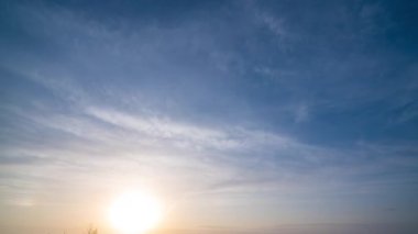 Güzel dramatik Hızlı Günbatımı ve Mavi Turuncu Gökyüzündeki Bulutlar. Güneş Ufkun üzerinde Sahada Batıyor.