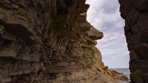 Movimiento de cámara desde una costa rocosa con piscinas de marea hacia el mar. Con una capa en el fondo — Vídeos de Stock