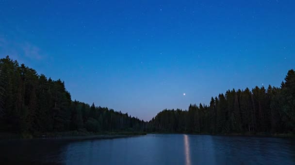 Ночное небо с облаками, освещенными звездами над горным озером и силуэтом деревьев. — стоковое видео