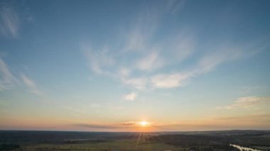 Yavaş sol kamera hareketi. Mavi gökyüzü ile doğal yeşil buğday tarlası ve güneşli bir günde bulutlar, gün doğumu. Doğal arka plan. Tarım arazisi, güzel renkli buğday, zaman aşımı, 4k hiperhız.