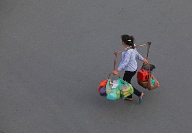 kadın alışveriş sonra paketleri bir sopa ile bir sürü sırtında taşıyor.