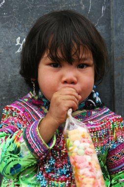 Şeker yiyen kimliği belirsiz bir Hmong kızının portresi