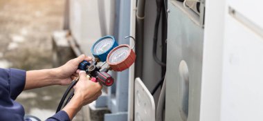 Teknisyen klimayı kontrol ediyor, klimaları doldurmak için ekipmanları ölçüyor..