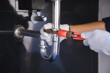 Tesisatçı ayarlanabilir anahtarla beyaz lavabo borusunu tamir ediyor..