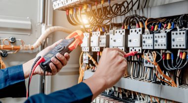 Elektrik mühendisi elektrik sistemi kontrol dolabındaki elektrik akımını ve elektrik hattını test etmek için çoklu metre kullanıyor..