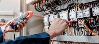 Elektrik mühendisi elektrik sistemi kontrol dolabındaki elektrik akımını ve elektrik hattını test etmek için çoklu metre kullanıyor..