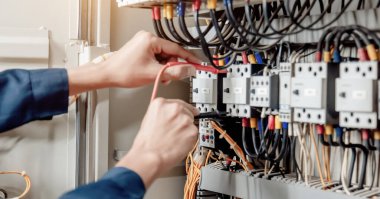 Elektrik mühendisi elektrik sistemi kontrol dolabındaki elektrik akımını ve elektrik hattını test etmek için çoklu metre kullanıyor..