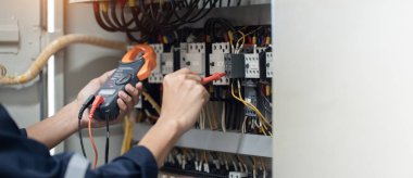 Elektrik mühendisi elektrik kabinesi kontrolündeki voltaj ve elektrik akımını ölçen bir testçi, elektrik sisteminin işleyişini konsept olarak kontrol ediyor .