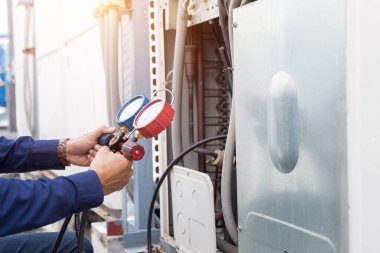 Teknisyen klimayı kontrol ediyor, klimaları doldurmak için ekipmanları ölçüyor..