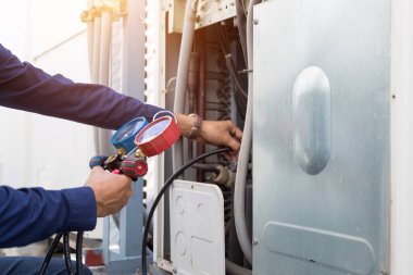 Teknisyen klimayı kontrol ediyor, klimaları doldurmak için ekipmanları ölçüyor..