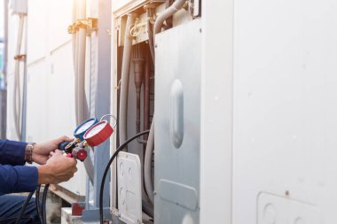 Teknisyen klimayı kontrol ediyor, klimaları doldurmak için ekipmanları ölçüyor..