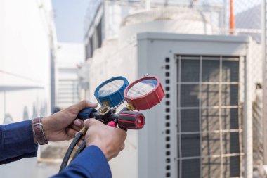 Teknisyen klimayı kontrol ediyor, klimaları doldurmak için ekipmanları ölçüyor..