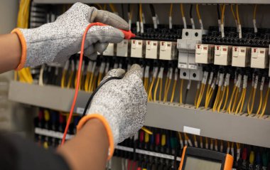 Elektrik mühendisi elektrik sistemi kontrol dolabındaki elektrik akımını ve elektrik hattını test etmek için çoklu metre kullanıyor..