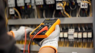 Elektrik mühendisi elektrik sistemi kontrol dolabındaki elektrik akımını ve elektrik hattını test etmek için çoklu metre kullanıyor..