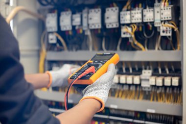 Elektrik mühendisi elektrik sistemi kontrol dolabındaki elektrik akımını ve elektrik hattını test etmek için çoklu metre kullanıyor..