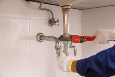 Tesisatçı ayarlanabilir anahtarla beyaz lavabo borusunu tamir ediyor..